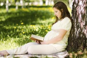 Pregnant woman reading outside