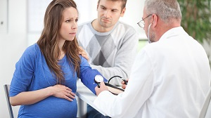 A worried pregnant woman talking with a doctor