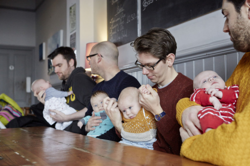 Dads holding babies in cafe