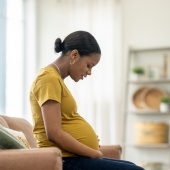 Pregnant woman sitting on a sofa and looking at her tummy