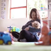 Parent breastfeeding child in playroom