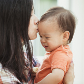 Parent kissing baby on the forehead