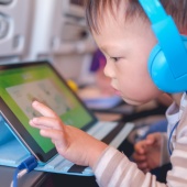 Young child playing on an iPad wearing headphones