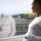 Pregnant woman looking out of the window
