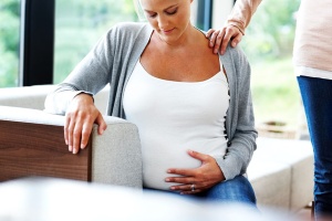 pregnant woman looking at bump with comforting hand
