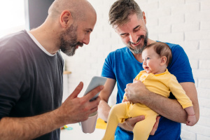 two dads taking picture of baby