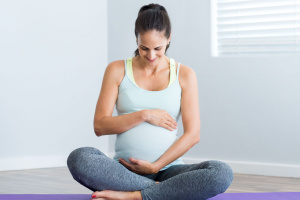 Pregnant woman sitting on a yoga mat.
