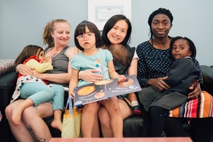 Three mums reading books to their daughters