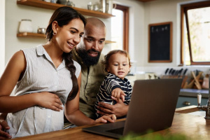 Expectant parents on laptop with child
