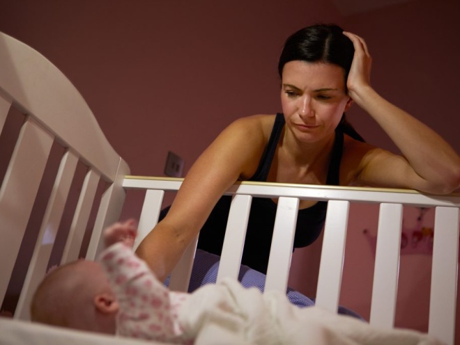 mum patting baby in cot