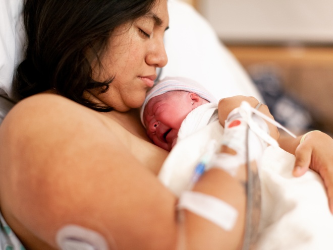 Parent recovering in bed after birth with baby