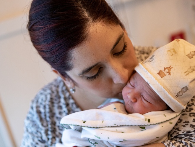 Parent kissing baby on their head after birth