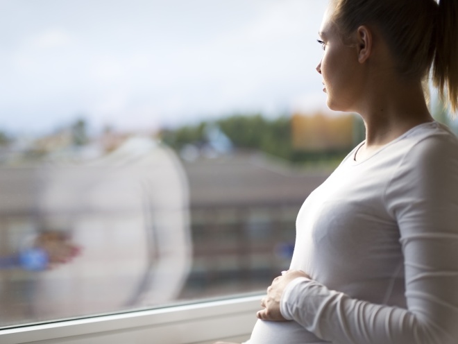 Pregnant woman looking out of the window