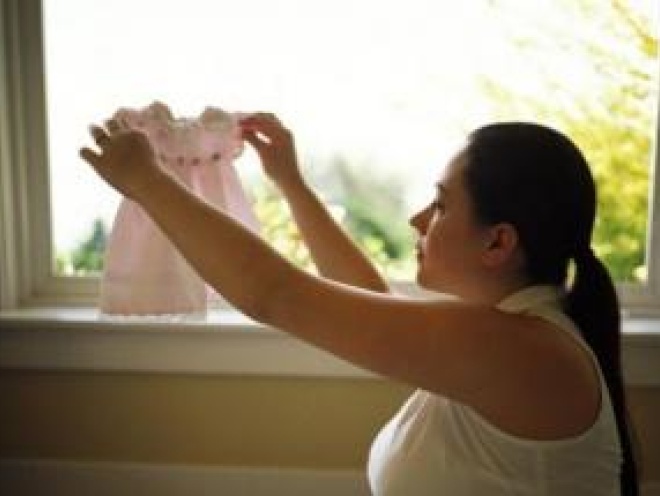 Woman holding baby clothes up to the window
