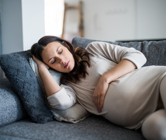 Pregnant parent lying on sofa