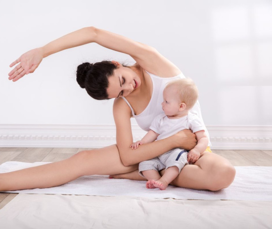 Mum holding her baby while doing yoga stretches