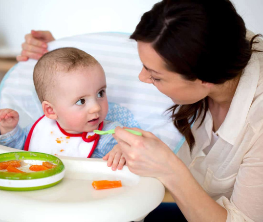 Mum feeding her baby in high chair