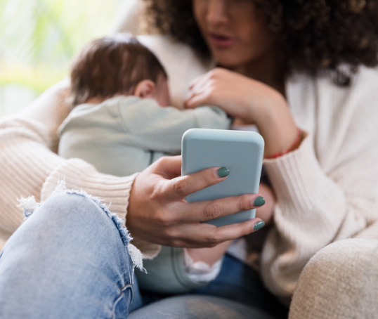 Mum breastfeeding while holding her phone