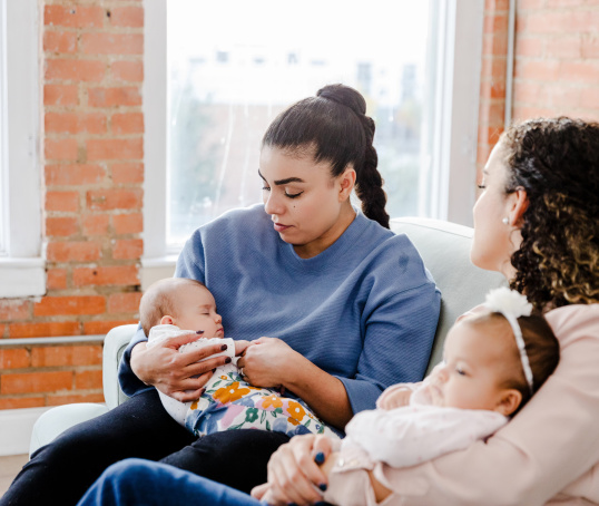 Two mums sitting holding their babies