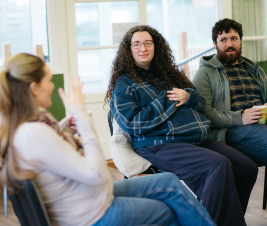Group of expectant parents sitting on chairs and talking at an antenatal class