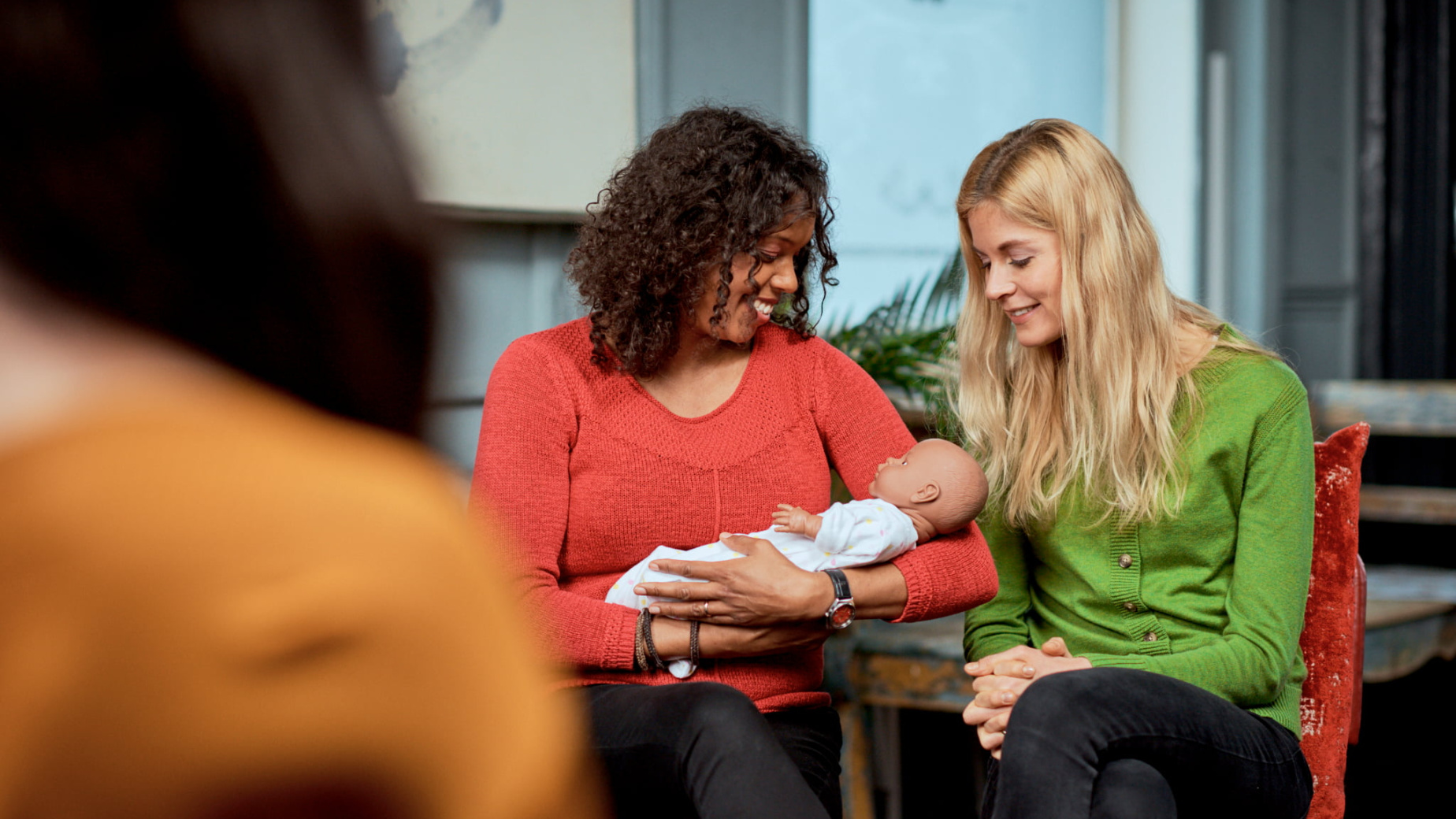 Two mums with a baby doll at an antenatal course
