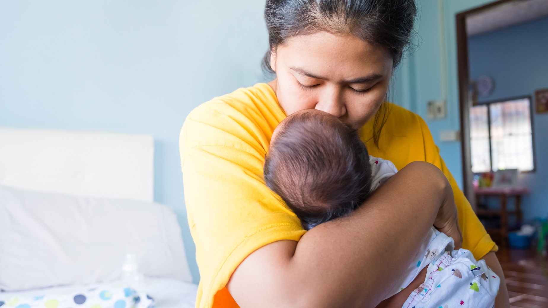 Mum holding and kissing newborn