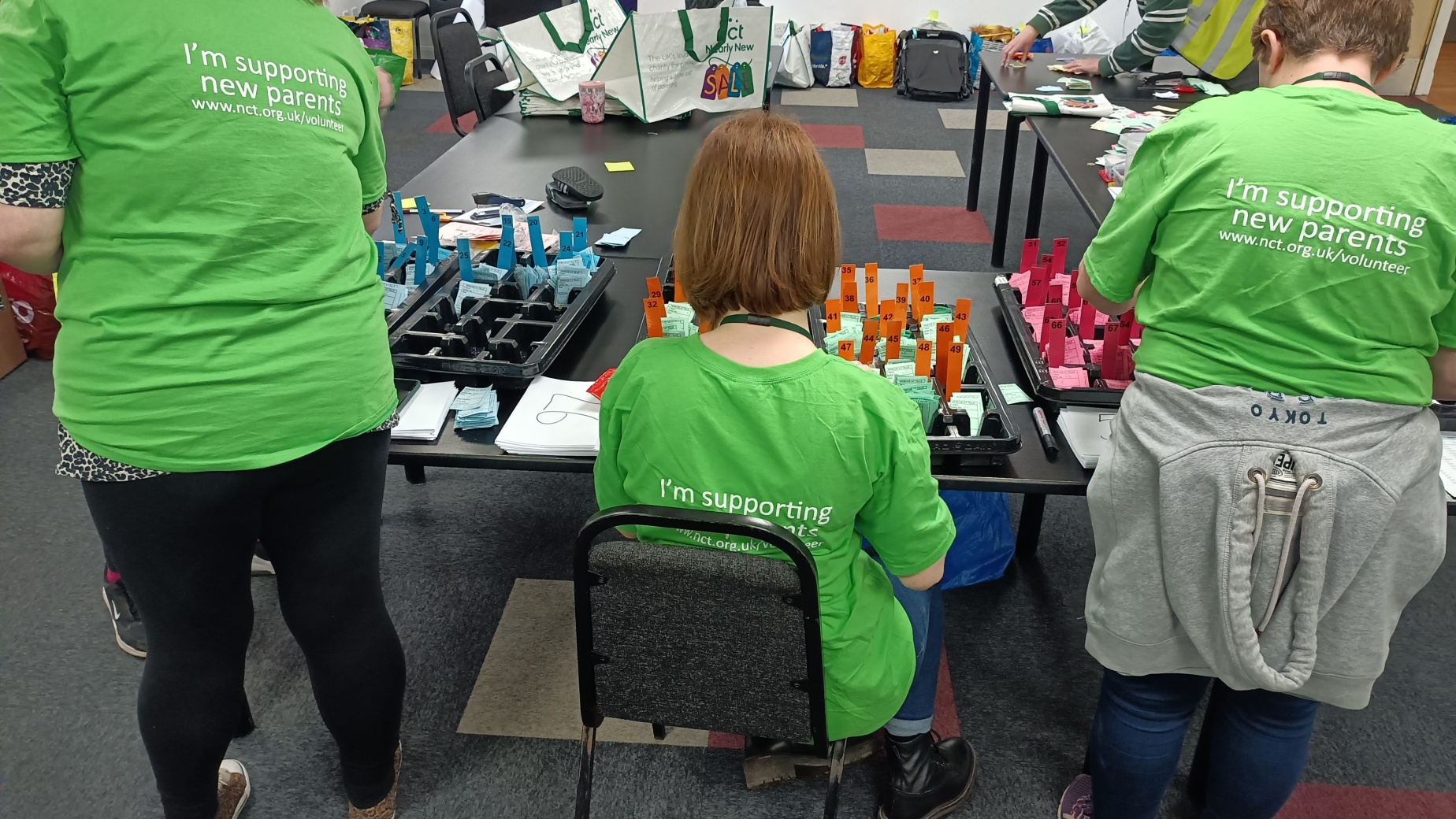 Three Nearly New Sales volunteers working at a table