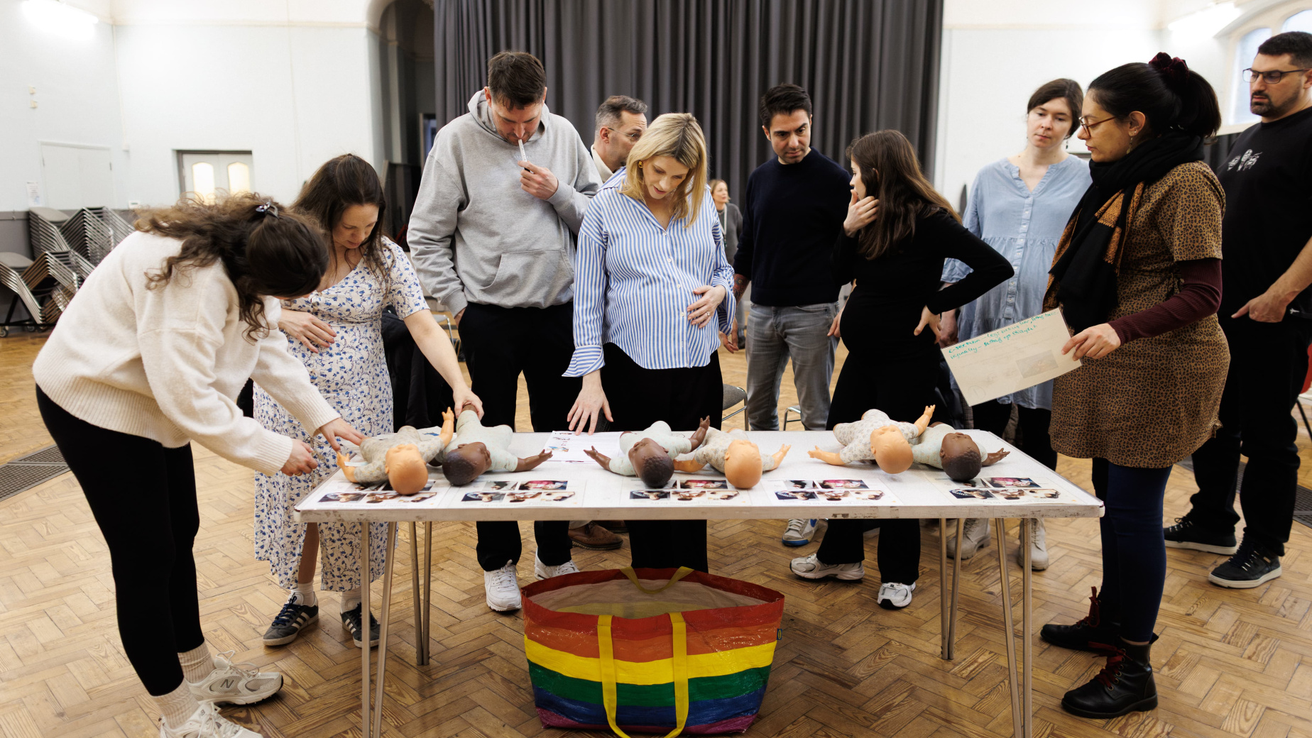 Group of parents standing around table looking at dolls at an antenatal class
