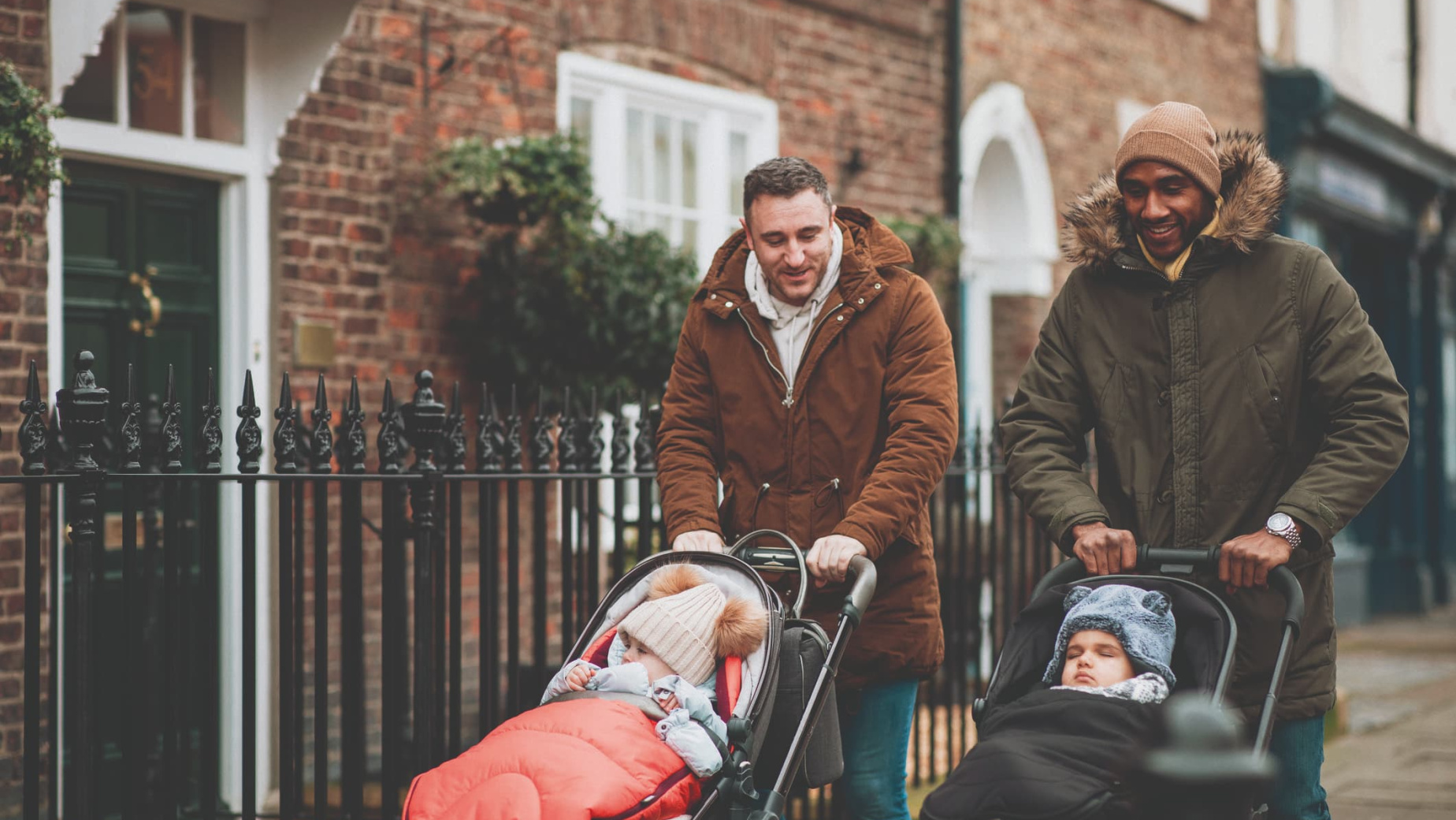 Dads pushing babies in buggies down a street