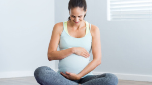 Pregnant woman sitting on a yoga mat.