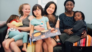Three mums reading books to their daughters