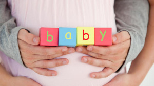Pregnany woman holding blocks that spell baby