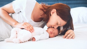 mum kissing newborn baby
