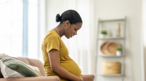 Pregnant woman sitting on a sofa and looking at her tummy