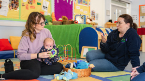 Peer supporter talking to mum holding baby