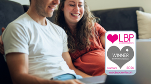 Pregnant couple sitting on a sofa looking at a laptop