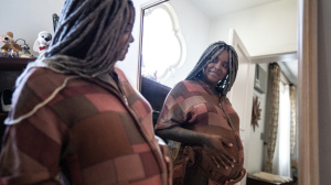 Pregnant woman or birthing person looking in a mirror