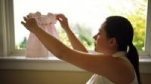 Woman holding baby clothes up to the window