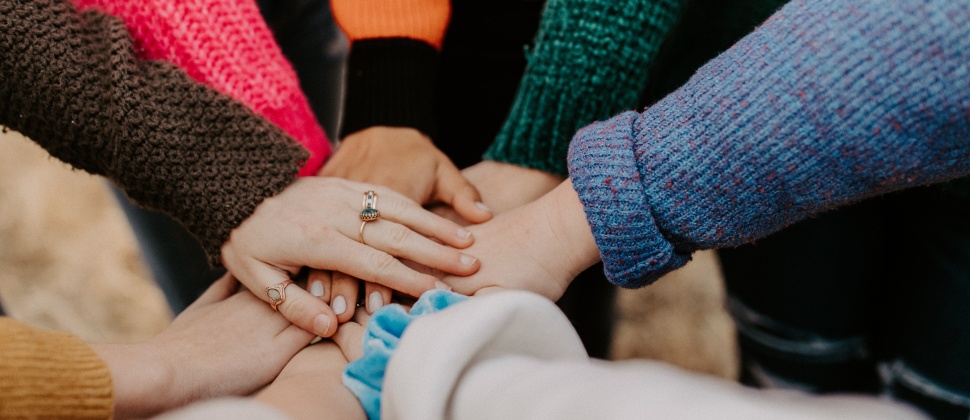 Image shows a circle of arms piling their hands on top of each other