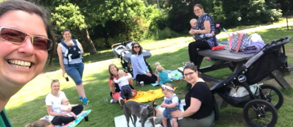 smiling parents and babies sitting on rugs in a park