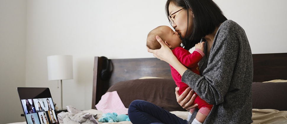 Mother on bed with baby and laptop