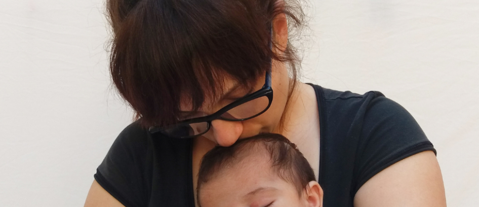 Mother kissing top of baby head