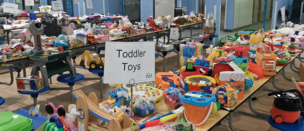 Image shows a large table full of children's toy and sign reading 'Toddler Toys'