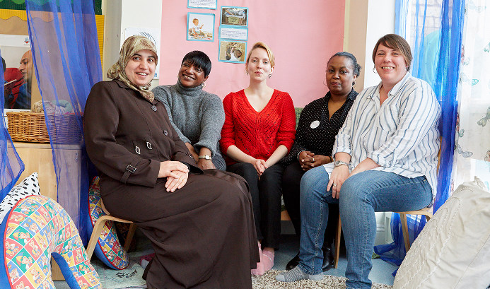 Five women looking directly at the camera in a child care room